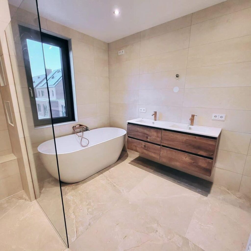 Gerenoveerde badkamer van Cam Badkamers met vrijstaand bad en houten badmeubel